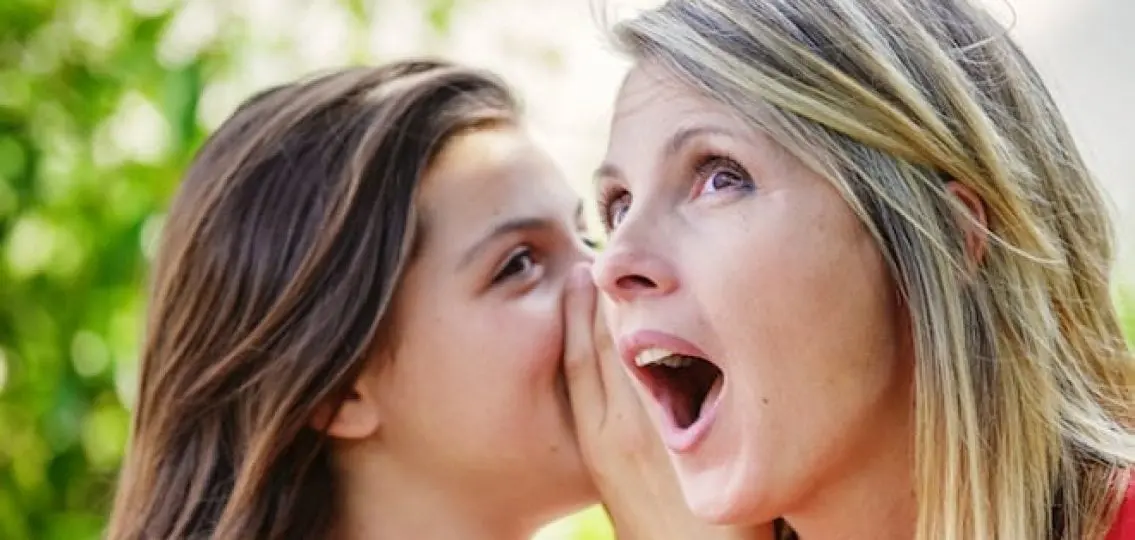 teen girl whispering to her surprised mother