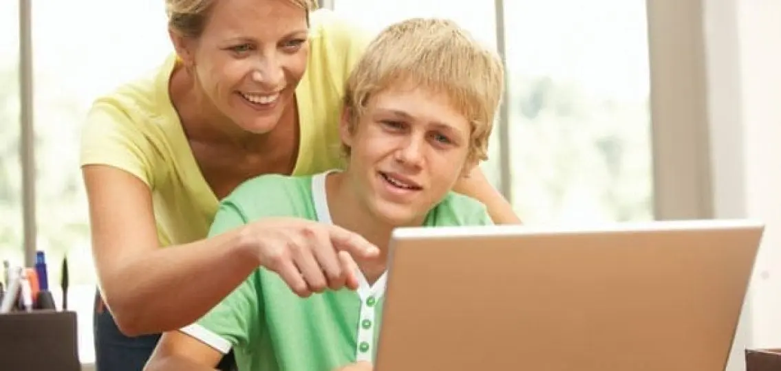 mom looking over her teenage son's shoulder to look at his computer