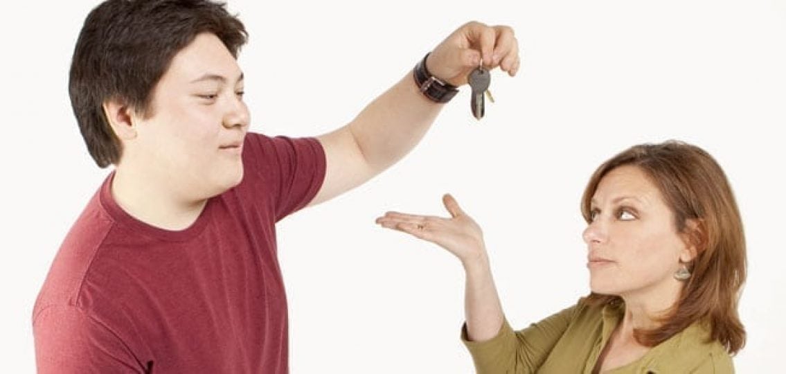 tall teenage boy holding car keys out of reach of his short and annoyed mother