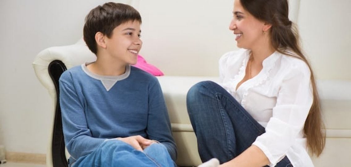 mom talking to teenage son sitting in front of the couch