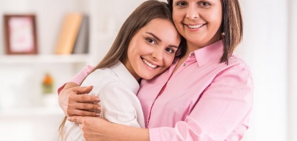 mom hugging her daughter and smiling in a nice house