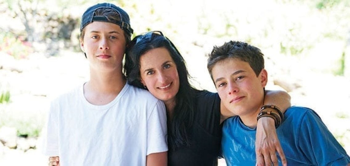 mom smiling and hugging her two teen sons