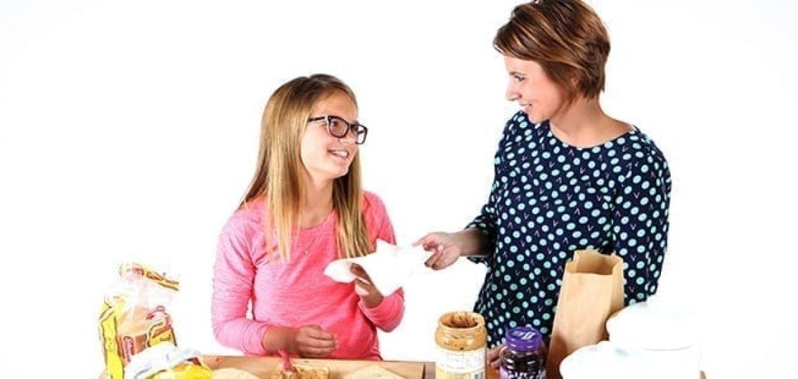 mom and daughter making sandwiches together and smiling