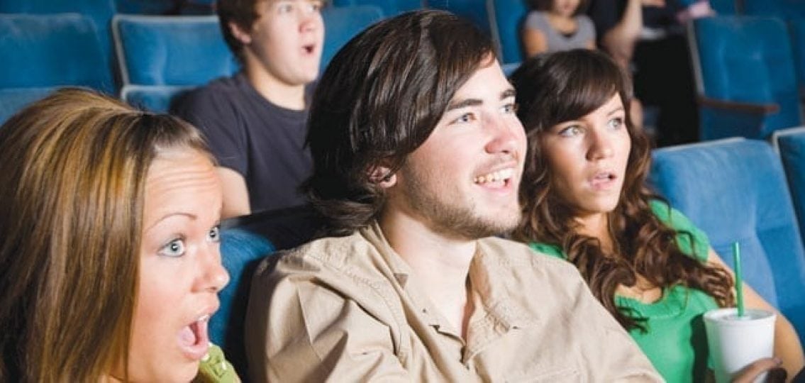 teenagers in shock watching a movie in a theater