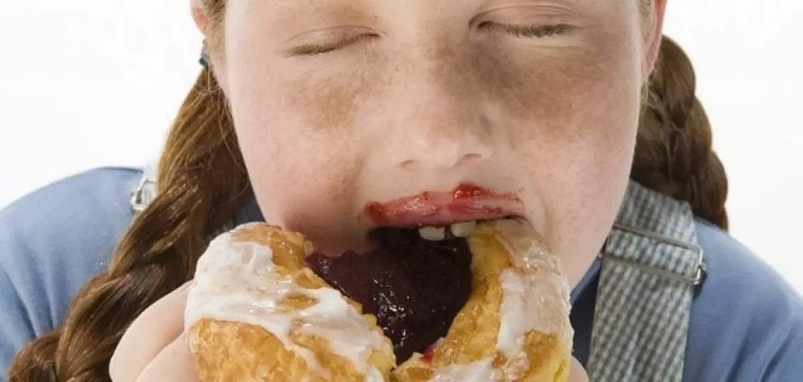 overweight teenage girl eating a messy pastry