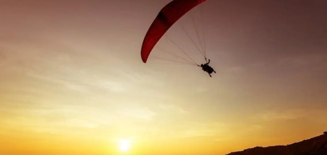 person parachuting with the sunset in the background