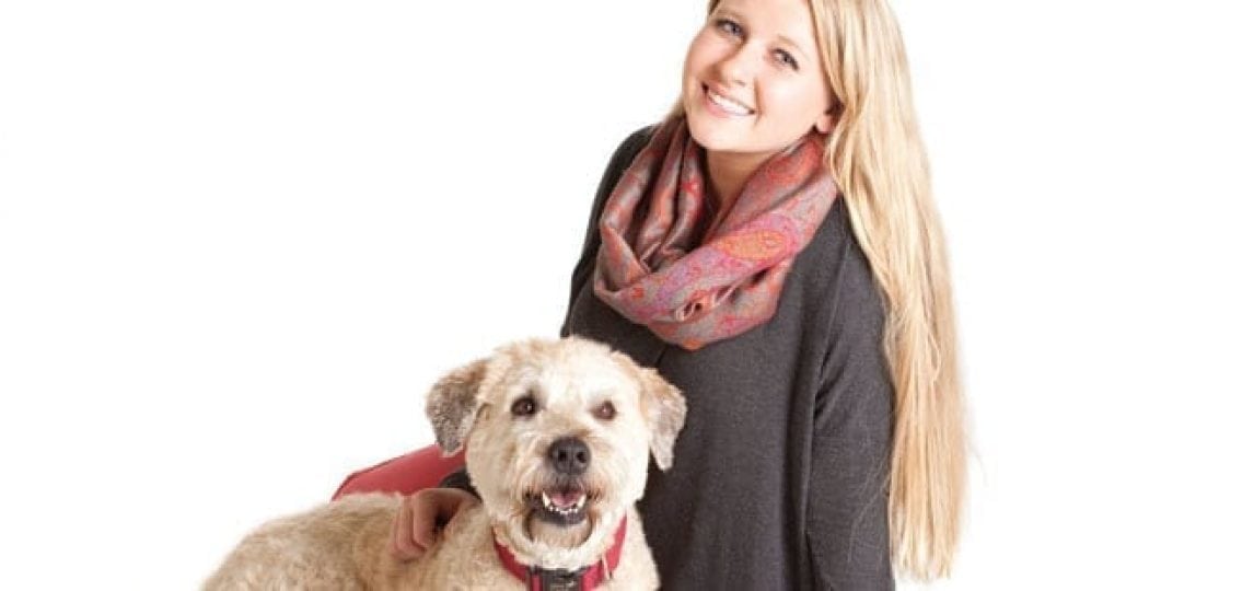 teen girl petting a dog and smiling on a white background