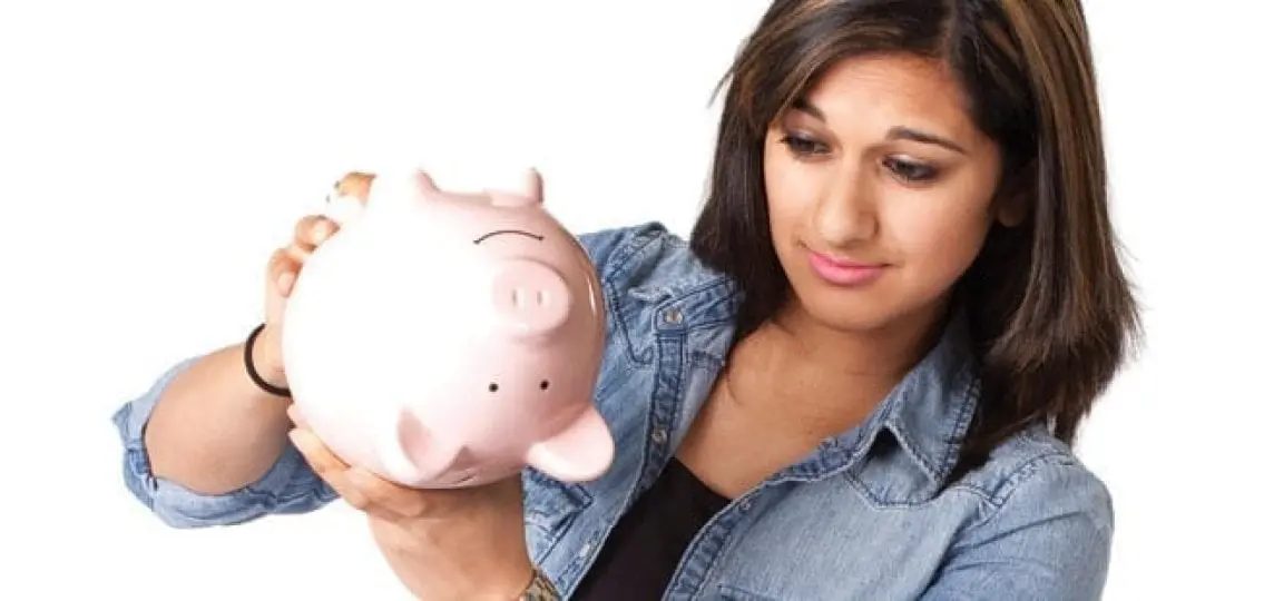 teen girl holding a piggybank upside down