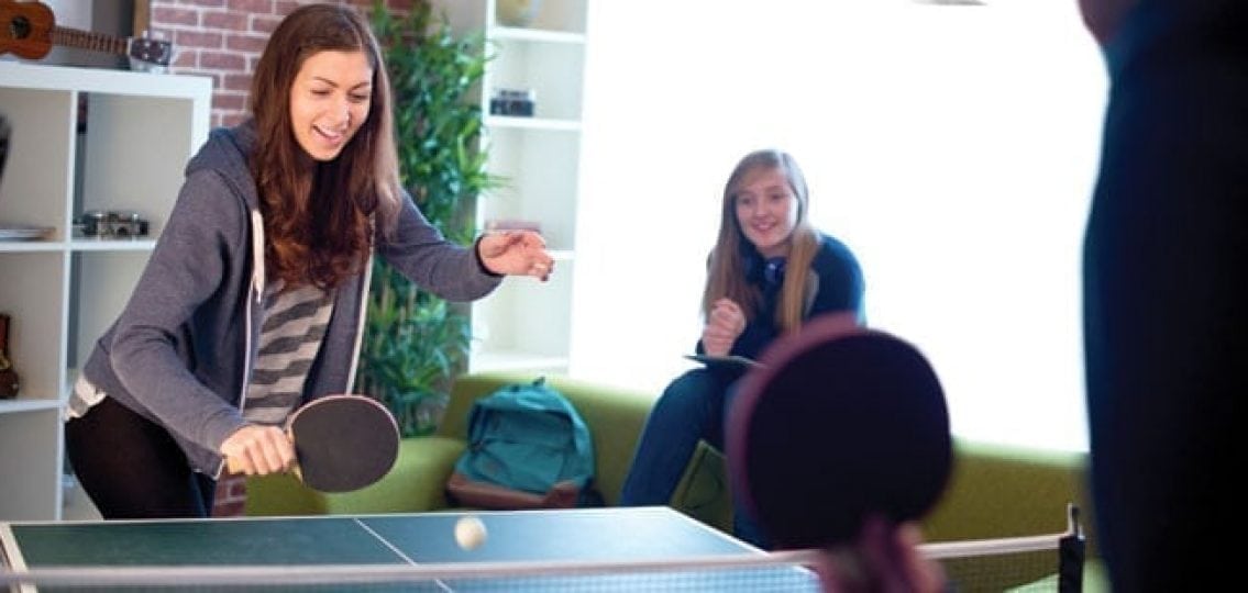 teen girls and dad playing ping pong