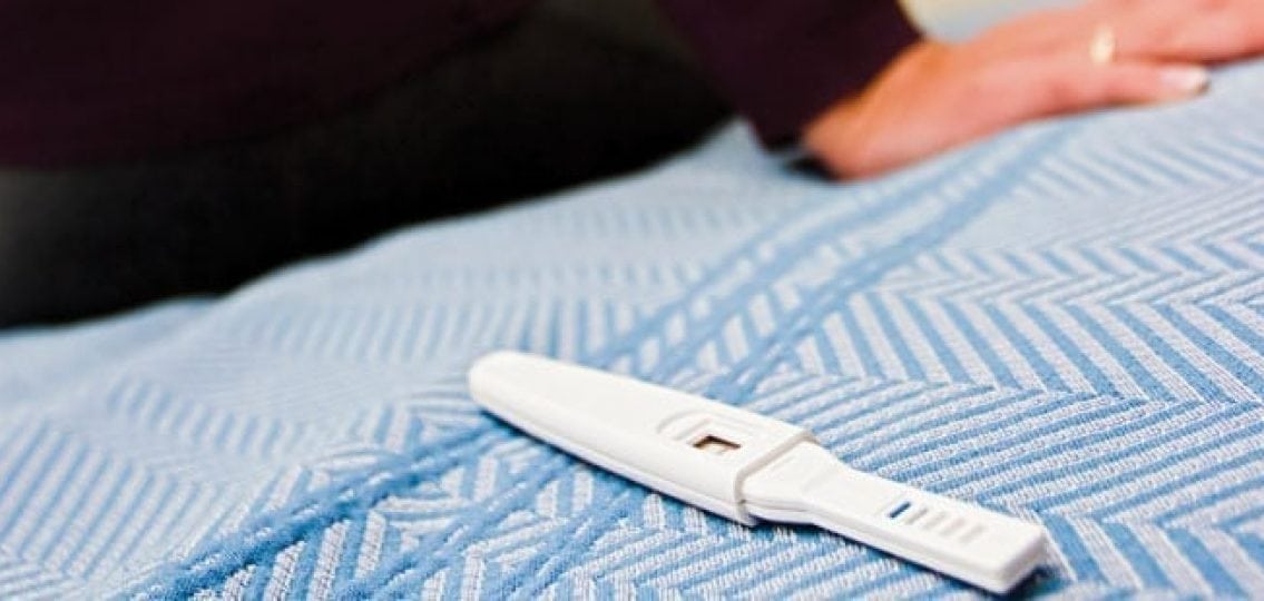 positive pregnancy test lying on a bed close up