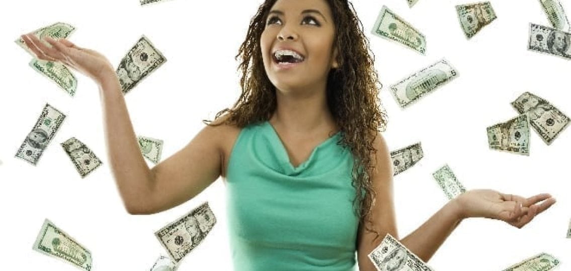 teen girl smiling as money rains down around her