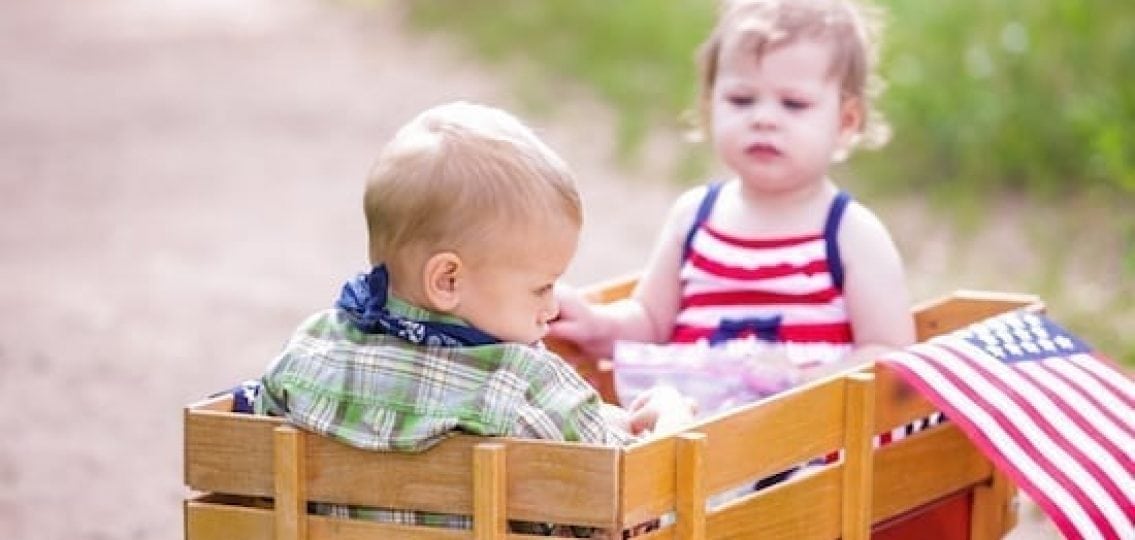 two toddlers in a wooden wagon