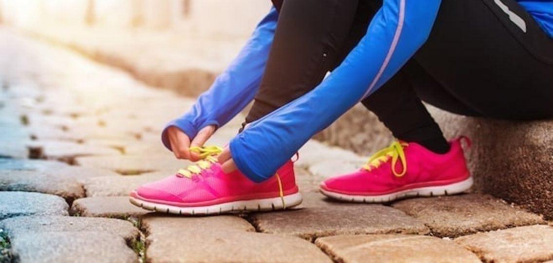 running-race woman tying her tennis shoes ready to run a race