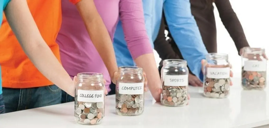 teens in front of various jars of money labeled college fund computer sports vacation and cat