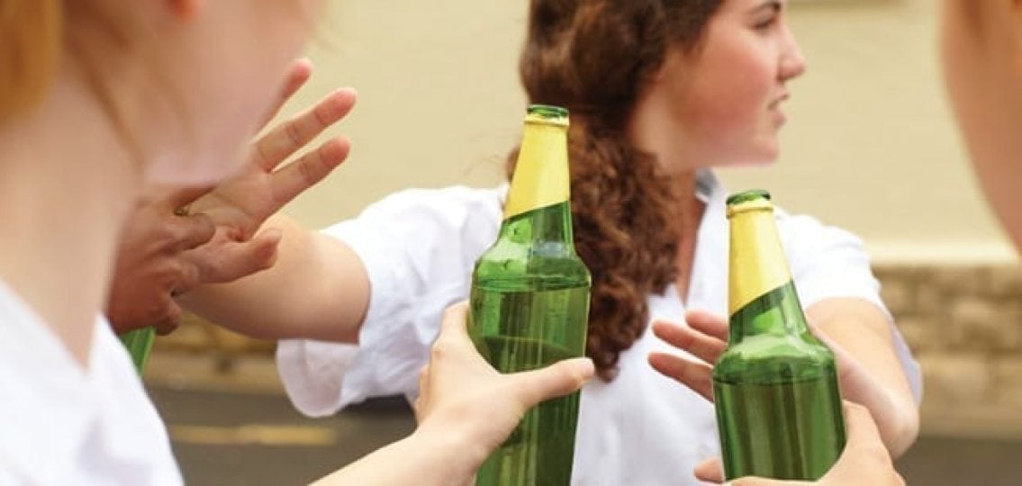 teenage girl holding her hands out to say no to alcohol being handed to her