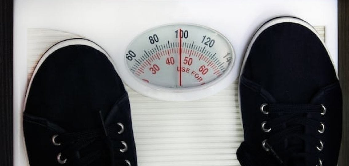 closeup of teen boy's sneakers standing on a scale weighing 100 pounds