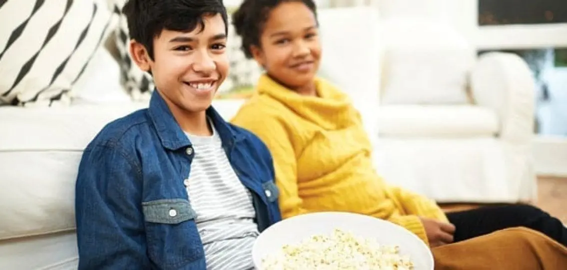 teen siblings with a bowl of popcorn watching tv