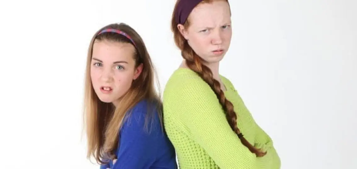 two angry teenage sisters scowling at the camera