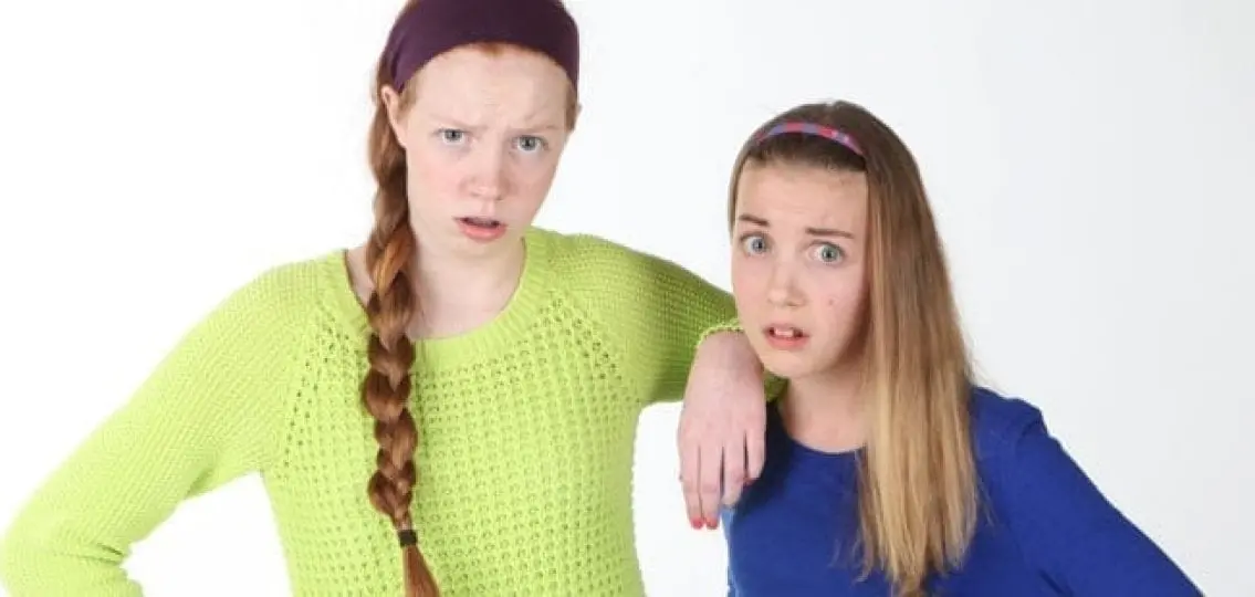teen sisters looking annoyed and incredulous looking at camera