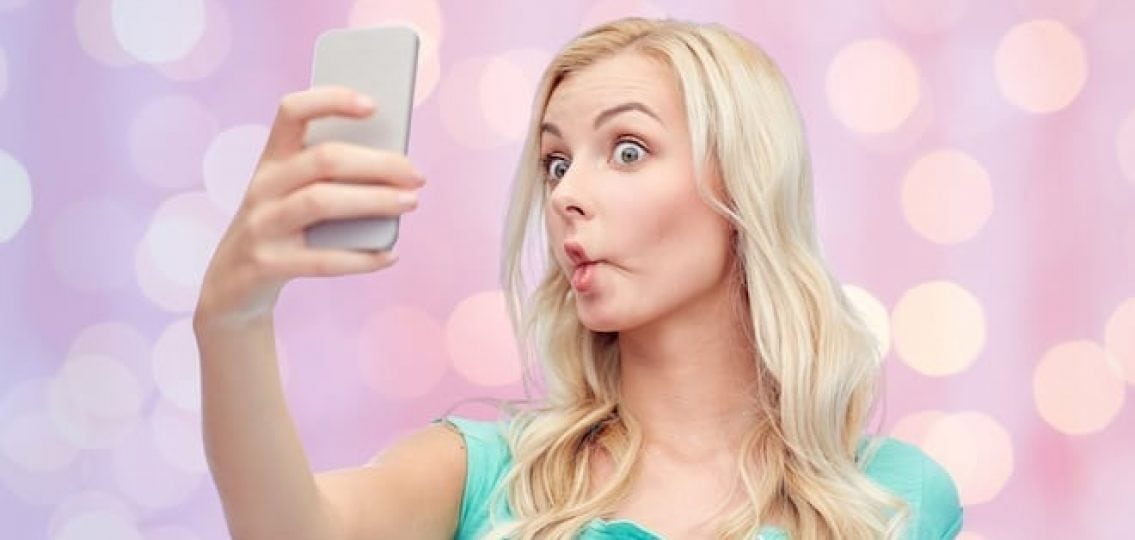 teenage girl making a silly face for a selfie pink and purple background