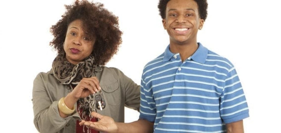 mom looking skeptical as she hands car keys over to a grinning teenage boy