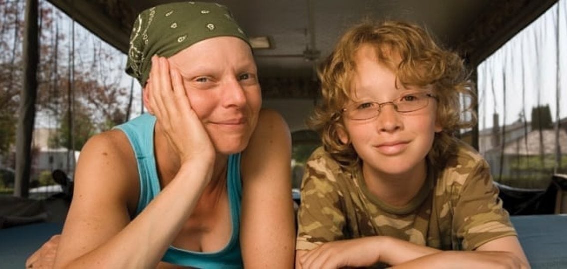 a teenage boy with a mother recovering from cancer chemotherapy smiling indoors