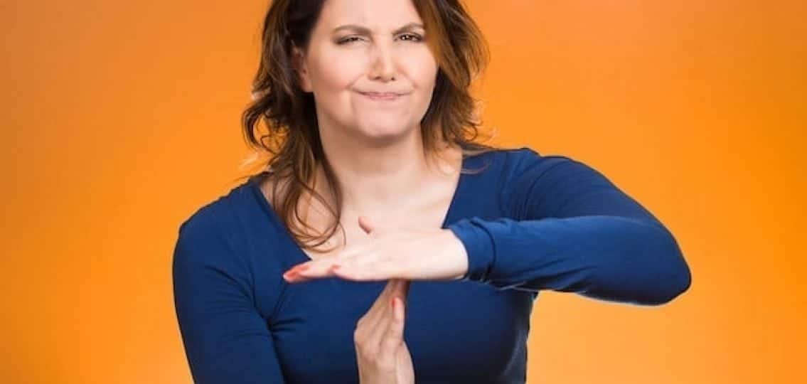 annoyed mom making a time out symbol with her hands orange background