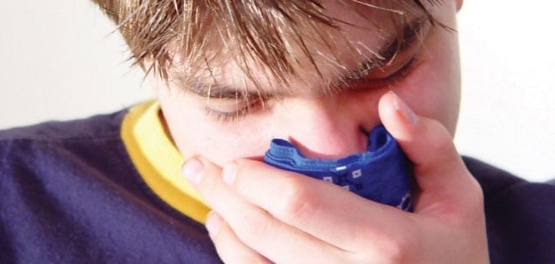 teenage boy sneezing into a handkerchief closeup