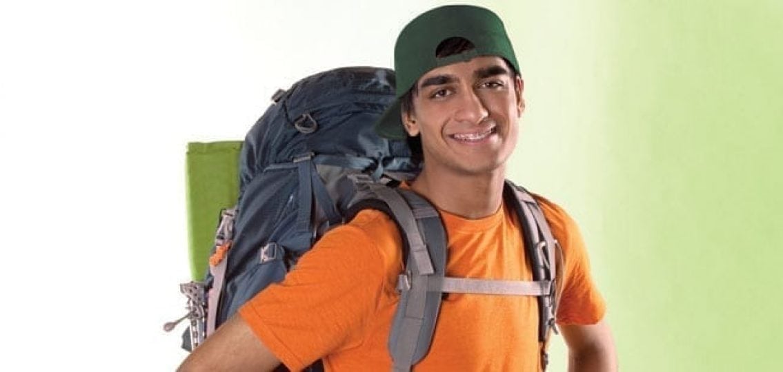 a teenage boy in a stuffed travel backpack ready to travel