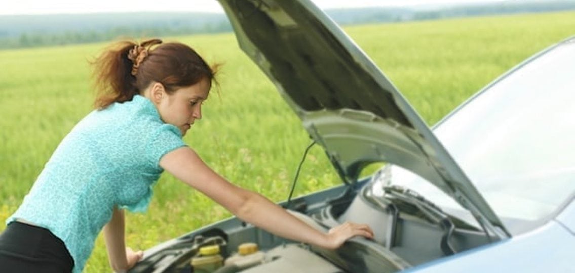 teen girl in front of an open hood of a broken car