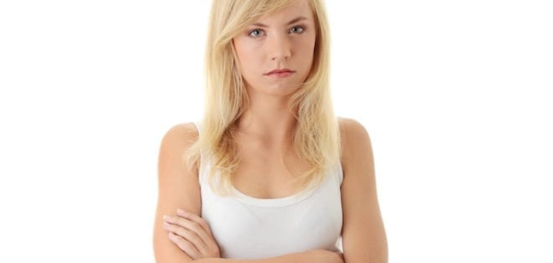 angry teen girl with arms crossed glaring at the camera white background
