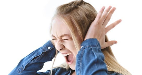 frustrated screaming teen girl covering her ears suffering from misophonia