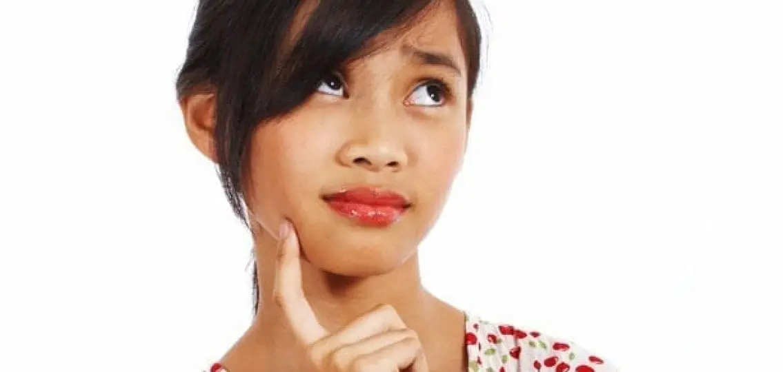young teen thinking with a finger to her chin on a while background
