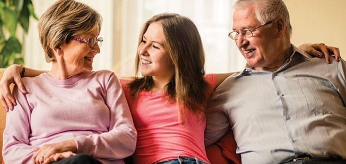 teen girl on couch with her arms around her grandparents