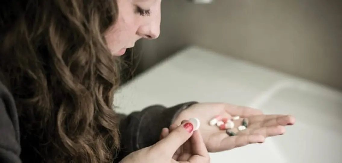teen girl with a handful of assorted prescription pills