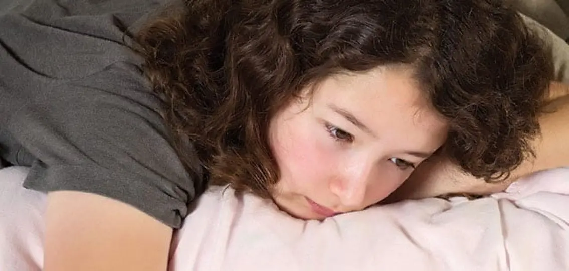 upset tired teen girl lying on her bed
