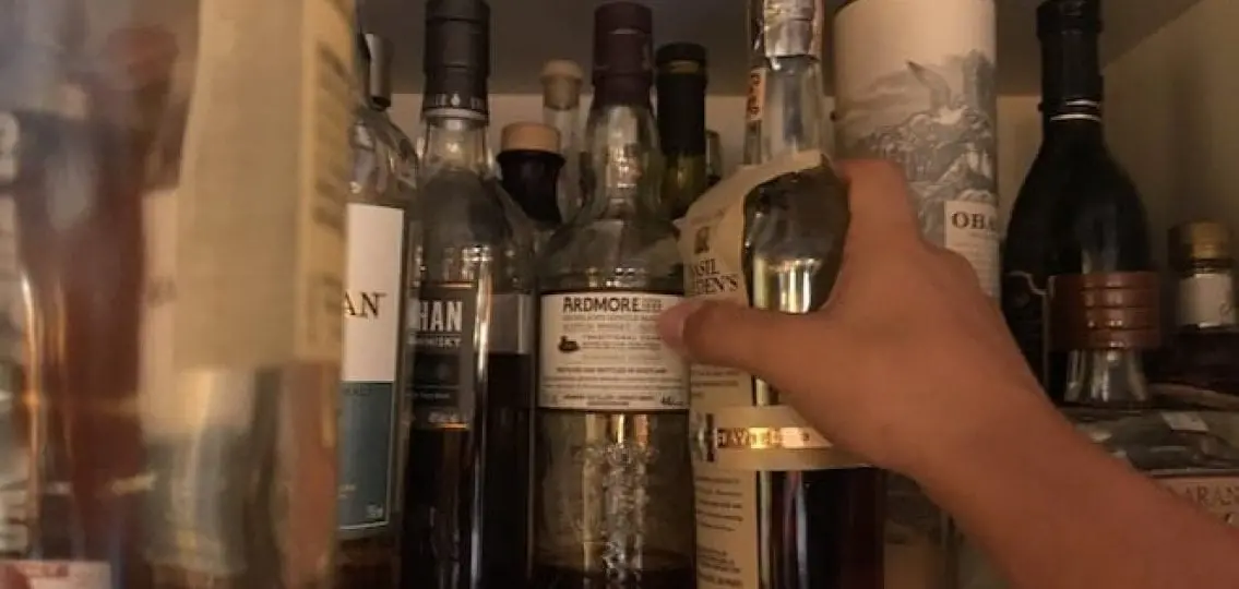 a cabinet full of alcohol as a hand grabs one