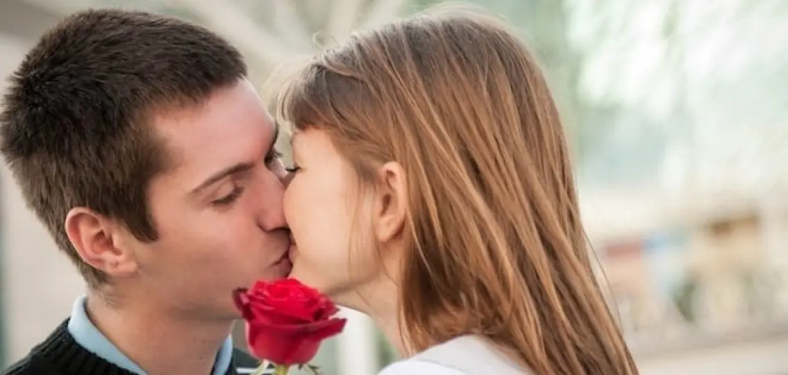 teenage couple kissing with a rose