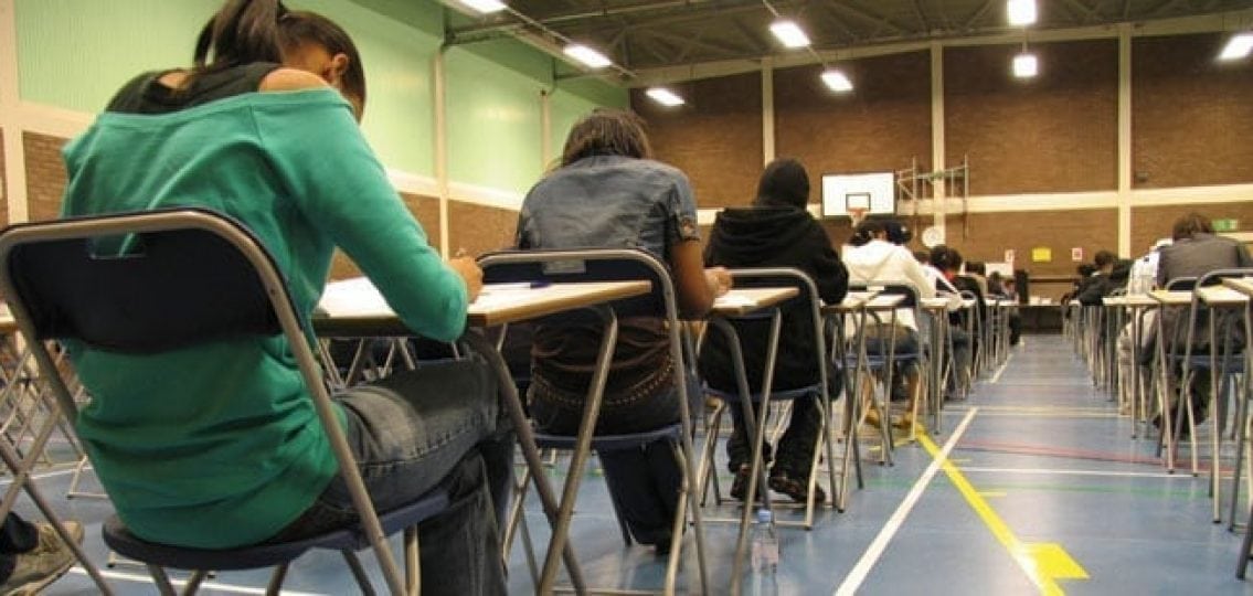 teens facing away at desks in the gym taking the SAT