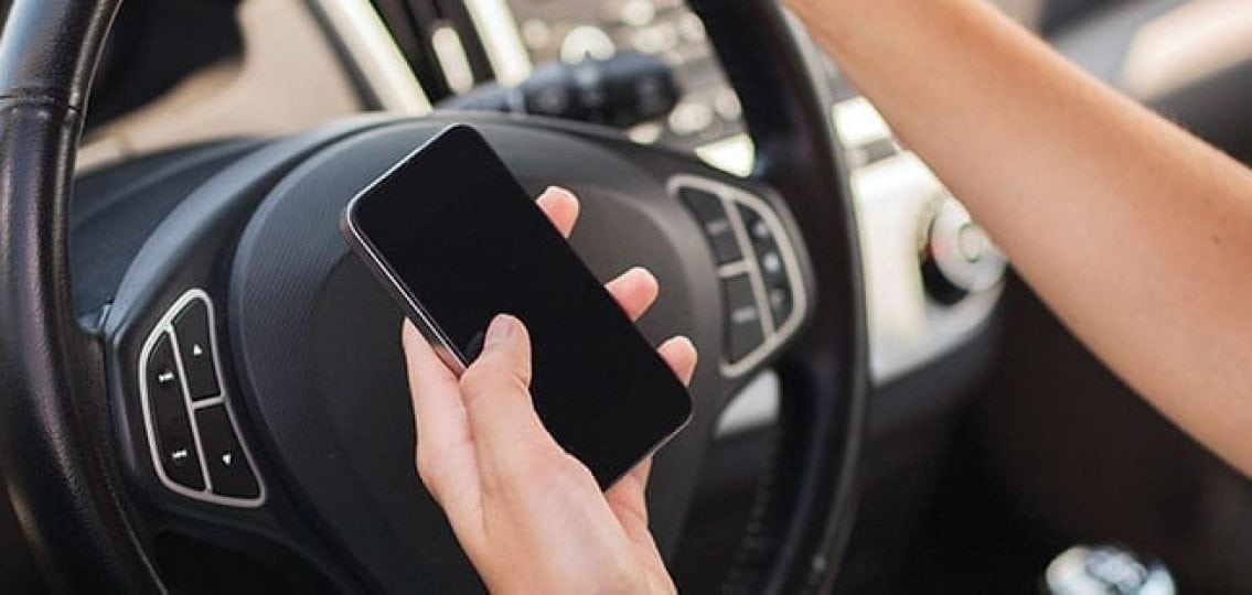 close up of a hand holding a phone while driving a car