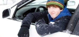 teenage boy hanging out of the car window in winter clothes covered in snow winter driving