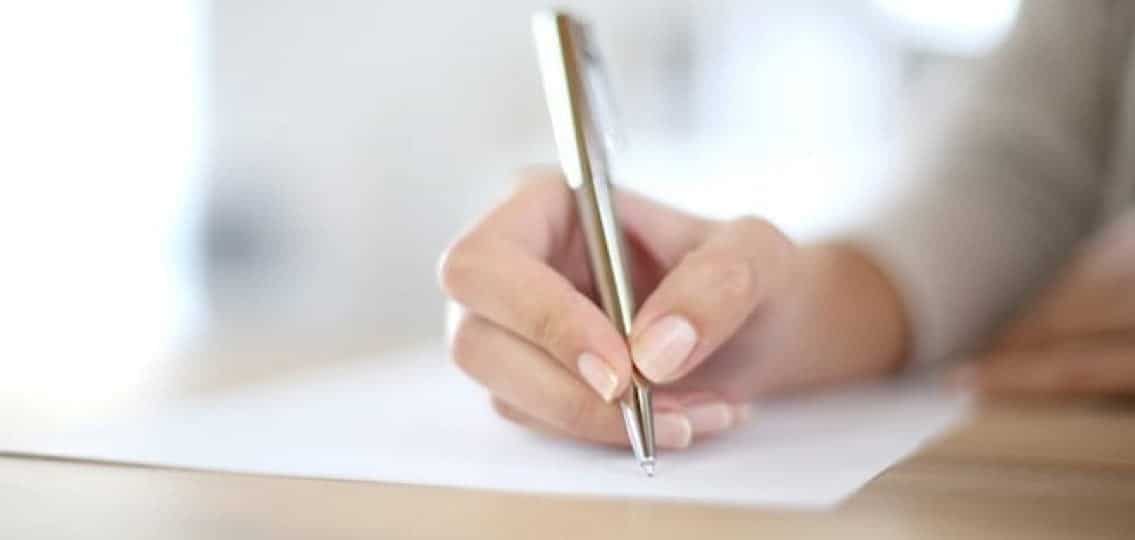 Mother writing letter to her teen son close up on pen