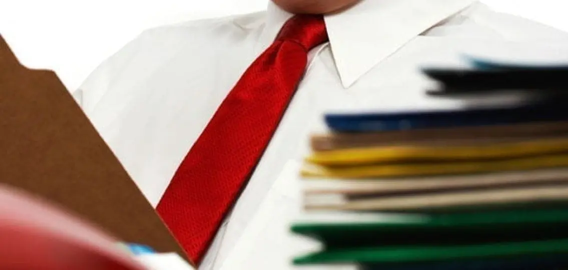 close up of a man wearing a red tie surrounded by folders