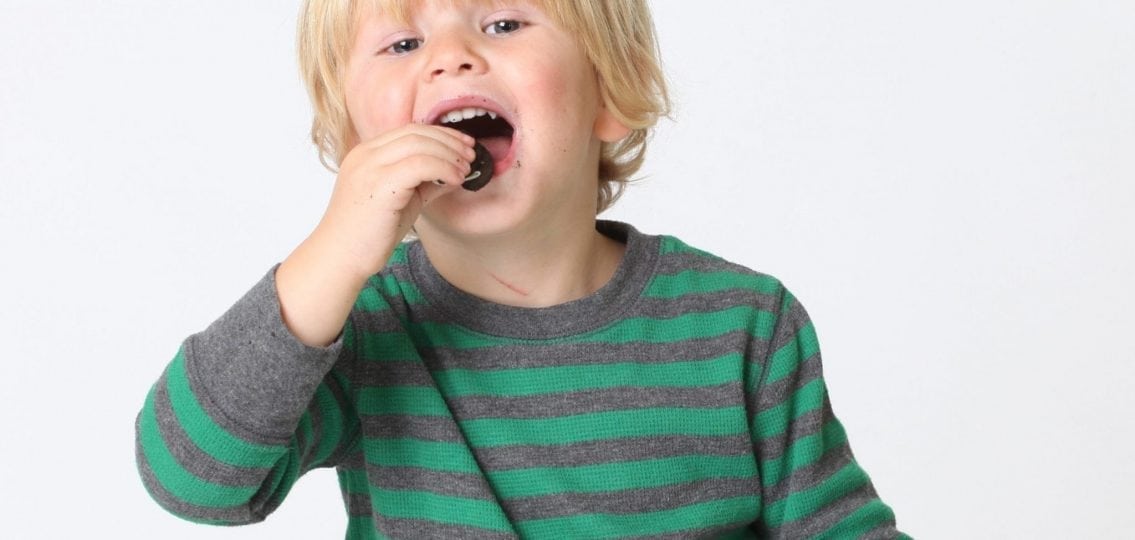 toddler eating an oreo with a paper cup in one hand