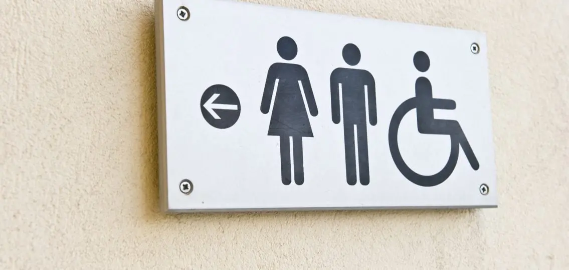 restroom sign pointing to bathrooms against a concrete wall