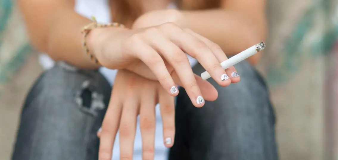 close up of a teen girl smoking either a cigarette or a joint