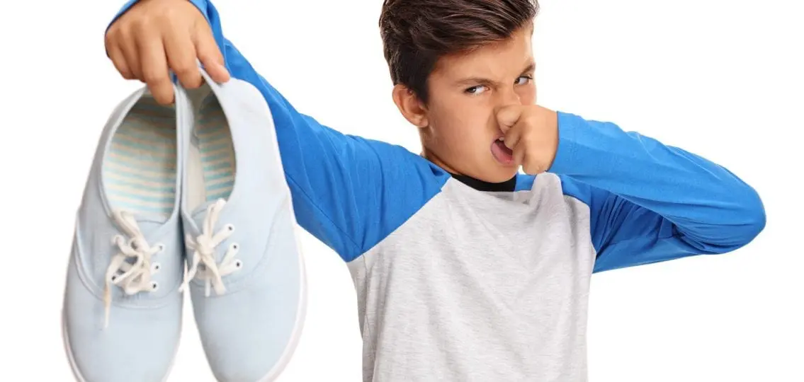 teen boy plugging nose at smelly shoes