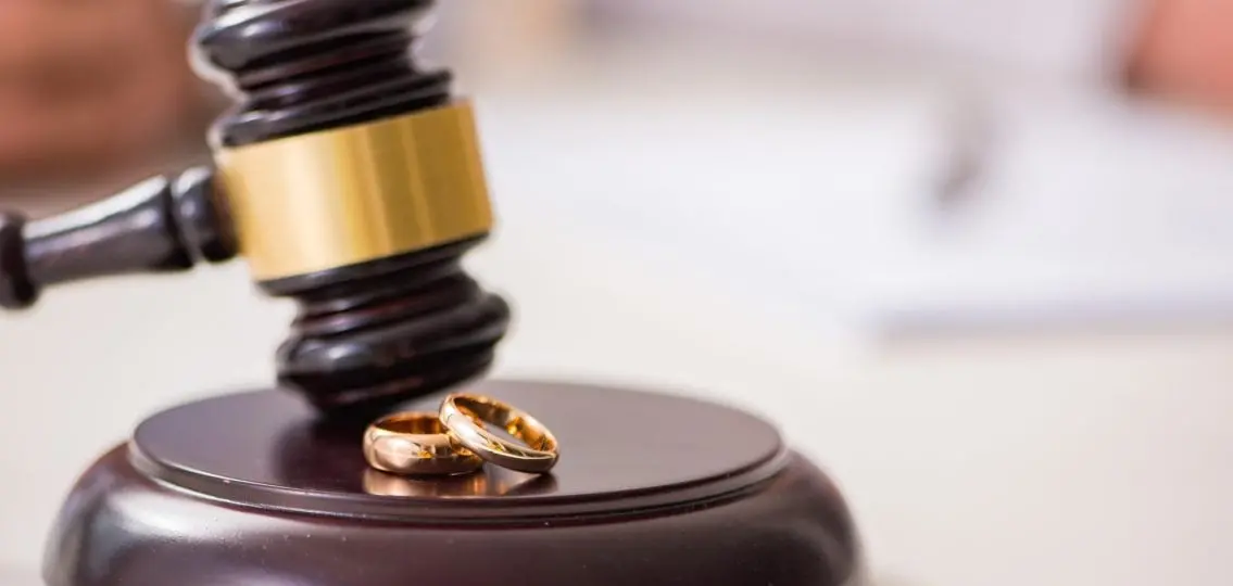 courthouse gavel next to two wedding rings divorce