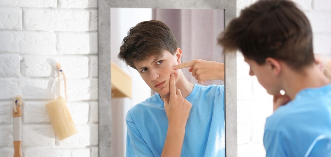 teenage boy with low self esteem looking in mirror