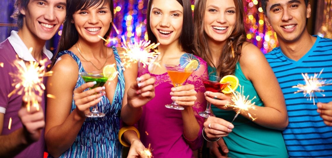teens celebrating new years with sparklers and colorful alcoholic drinks